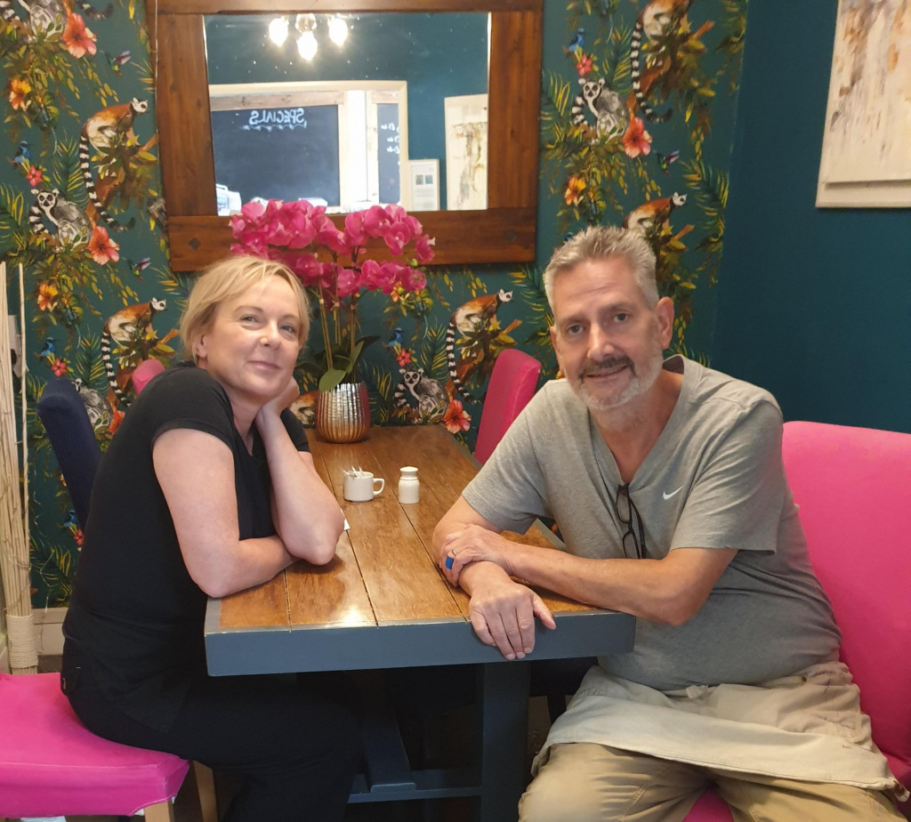 Two people sit at a cafe